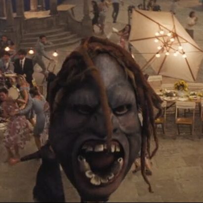 Model of the face of a grey-coloured troll from the film 'Artemis Fowl', mouth wide open and frowning. Its face is framed by several brown locs.