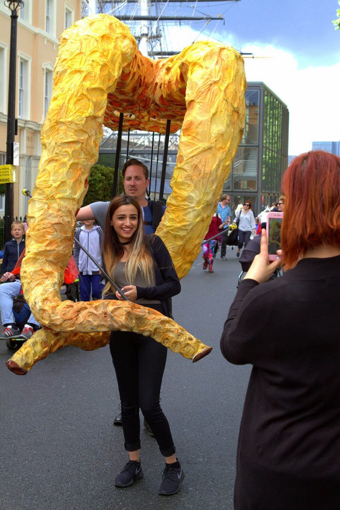 A person posing for a photo with a puppet of two giant squid tentacles.